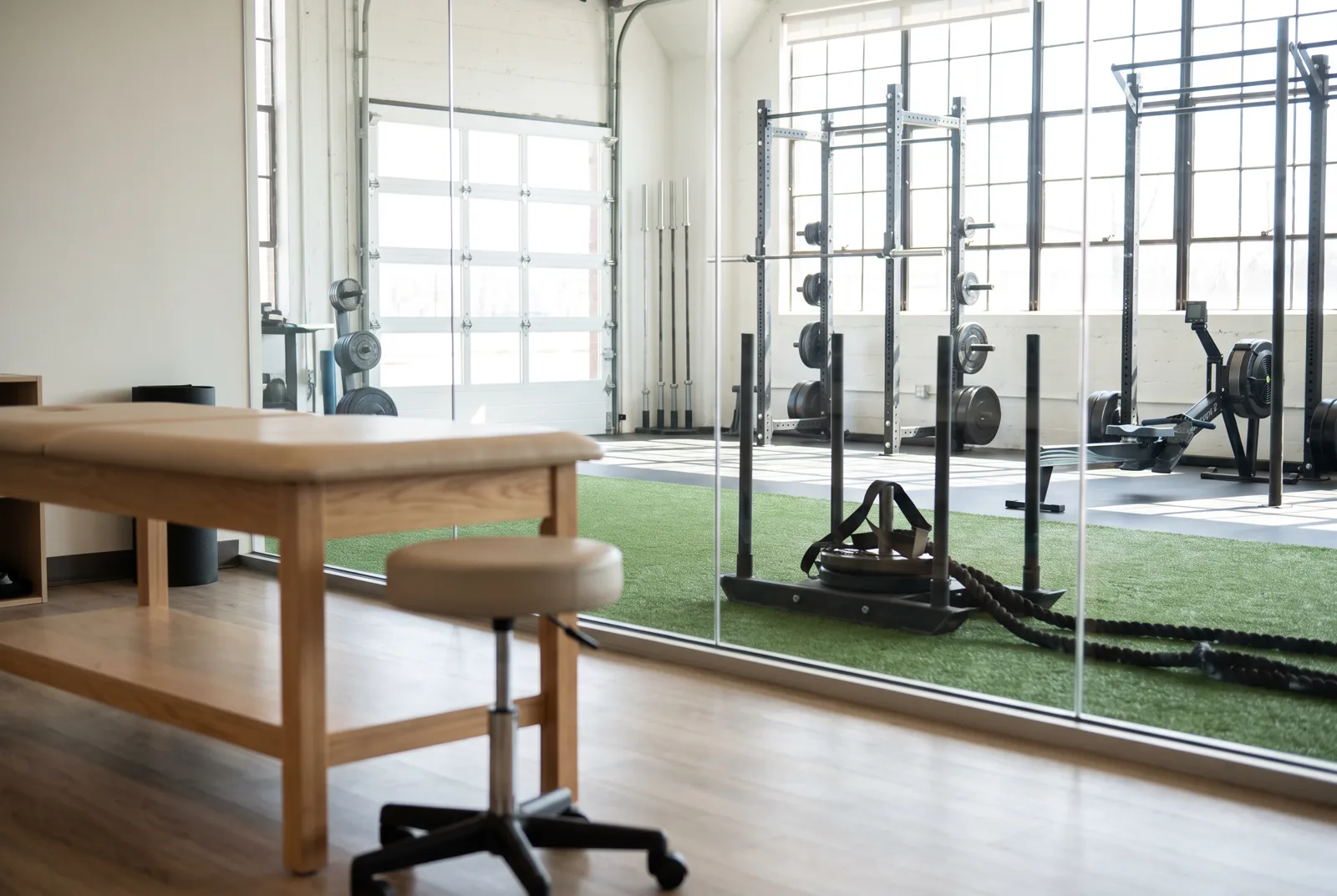 An open gym area with turf, a sled, battle ropes and barbell racks