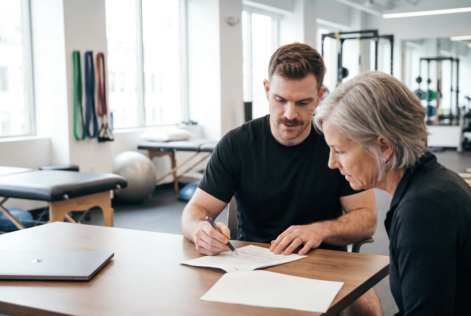 A physical therapist reviewing printed results with a client at a desk