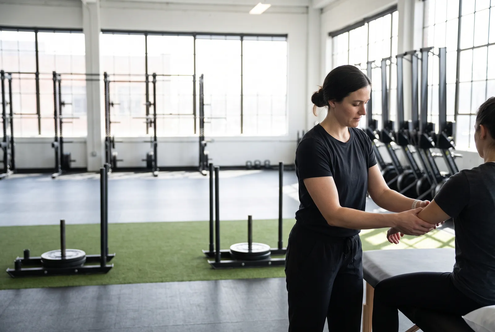 A gym training floor with squat racks, a turf area with sleds and rowers