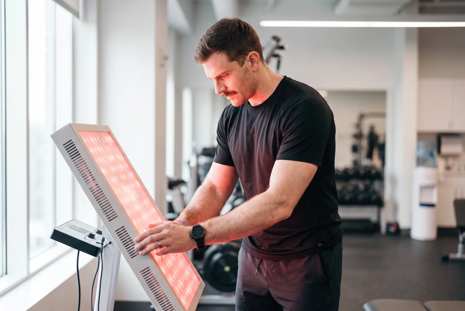 A physical therapist adjusting the angle of a red light therapy panel