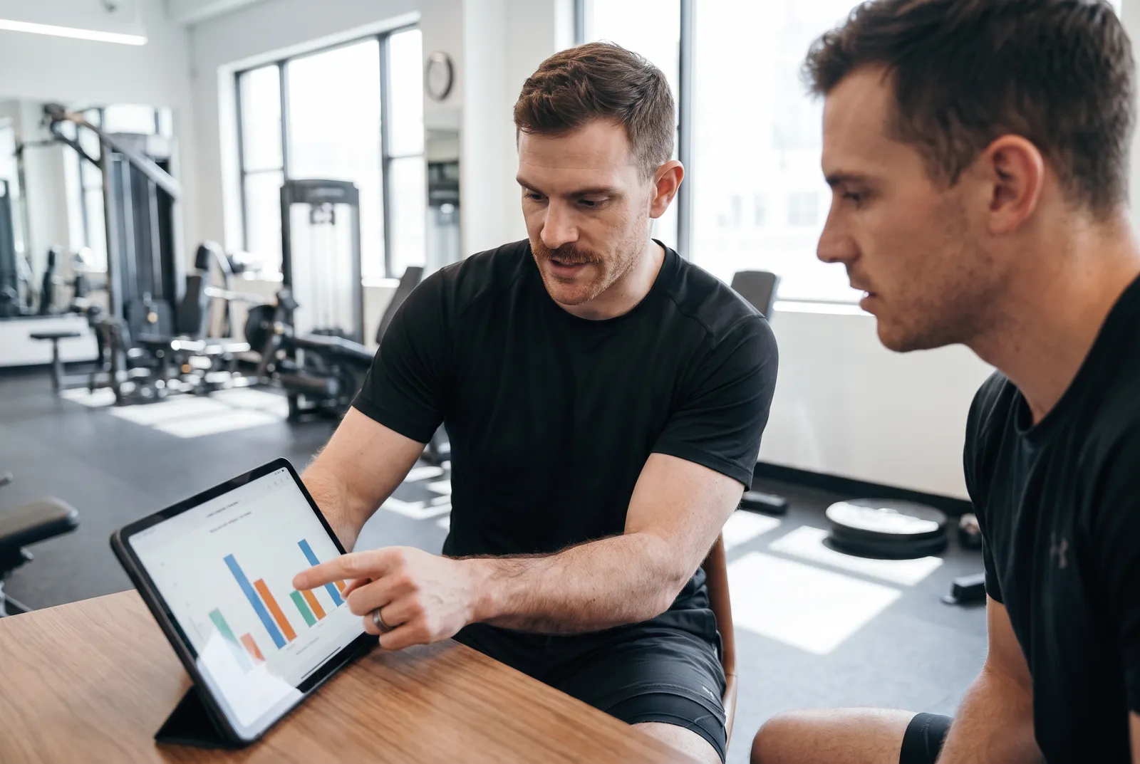 A physical therapist and an athlete looking at test results on a tablet