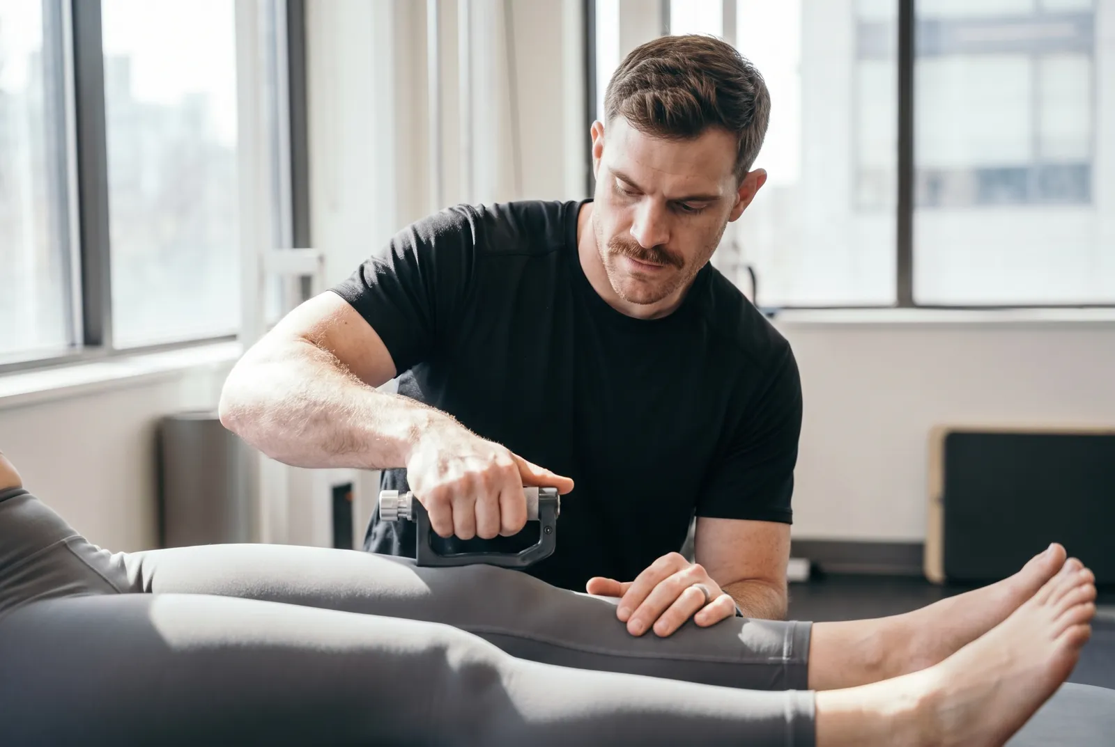 A physical therapist comparing leg strength with a handheld tester