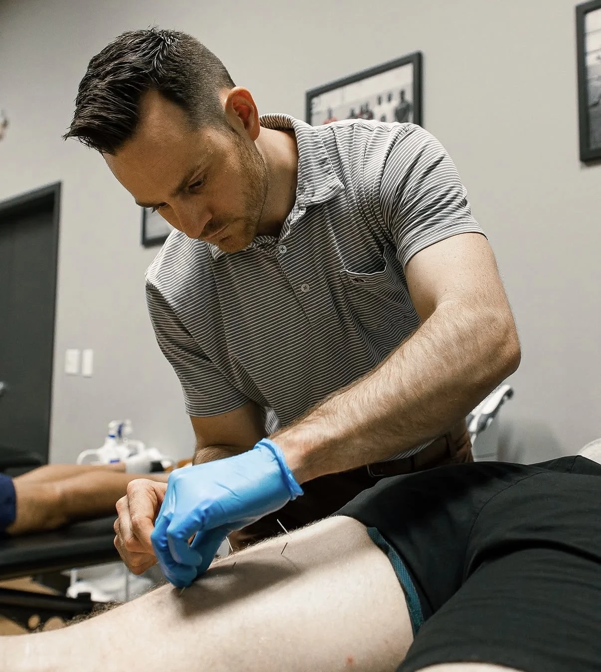 Storm Wilson performing dry needling on a patient's leg at MOTiV in Chattanooga